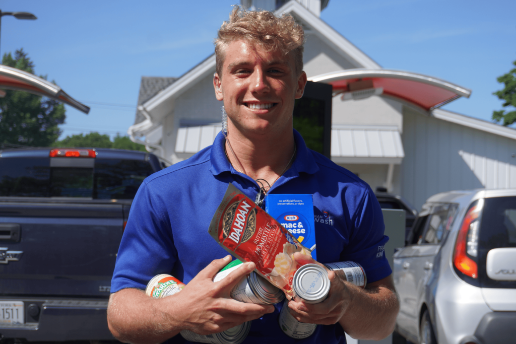 Smiling man holding boxes and cans of food